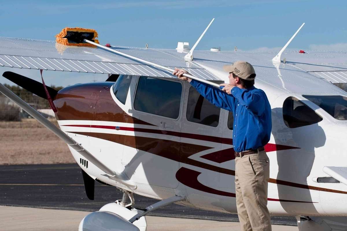 A man cleaning the wing of a small aircraft with a waterless mop kit aircraft, rv, boat, car